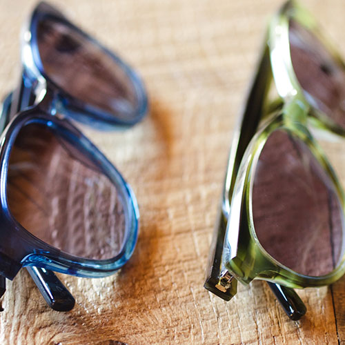 Two pairs of glasses lined up on wood table