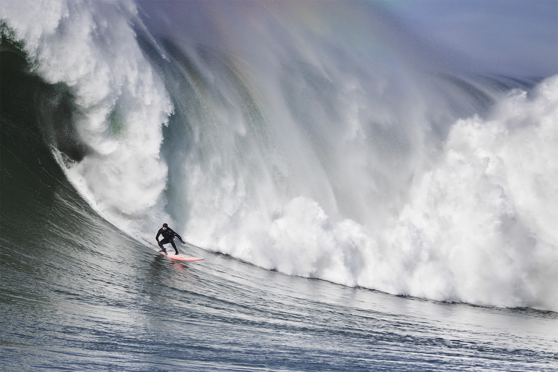 Person surfing in front of large wave